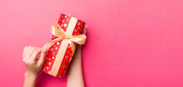 Dívka Ruce drží řemeslné papírové dárkové krabice s jako dárek na Vánoce nebo jiné dovolené na růžovém pozadí, horní pohled s kopírovacím prostorem. - Fotografie, Obrázek