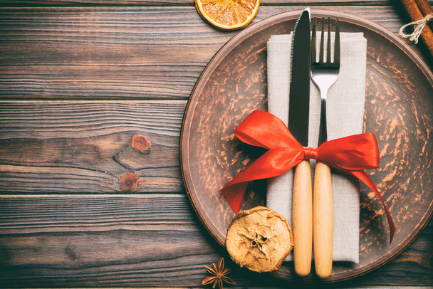 Κάτοψη γιορτινού δείπνου διακοσμημένο με αποξηραμένα φρούτα και κανέλα σε ξύλινο φόντο. Σύνολο από πιάτο, urensil και το νέο έτος διακοσμήσεις. Χριστουγεννιάτικη ιδέα με epmty χώρο για το σχεδιασμό σας. - Φωτογραφία, εικόνα