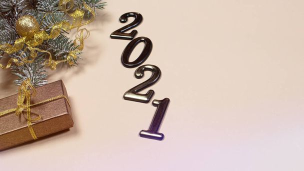 New Year's card with figures 2021, gift and spruce branch on a beige background with a place for copyspace text. Christmas, year of the bull. - Photo, Image