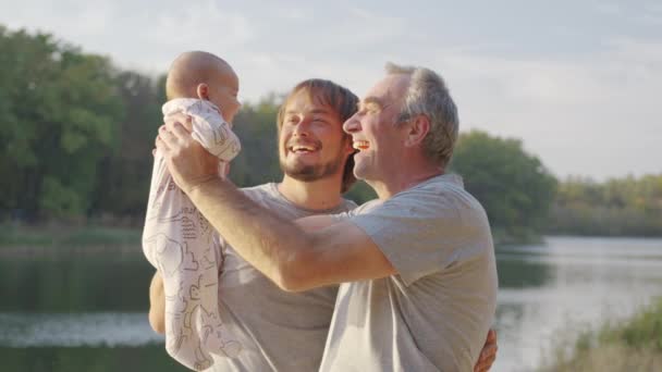 Három generációnyi férfi. Nagyapa, apa és az unokája. Naplemente, a folyó partja. - Felvétel, videó