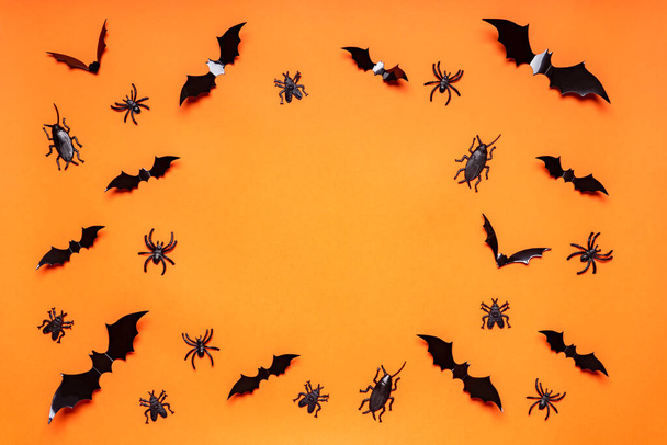 Halloween composition. Black bats, spiders, flies and bugs on orange background. Happy Halloween, trick or treat party concept. Flat lay, top view, copy space. - Φωτογραφία, εικόνα