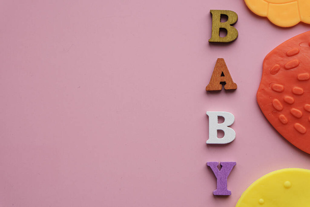 Childhood, love, care, hygiene, infants - The word baby teeth laid out of colored wooden letters on a pastel pink background. large colored toothpick toy. teething - 写真・画像