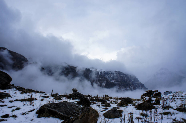 Buluttaki dağ kış manzarası. Taşlar, karda kayalar. Himalaya, Nepal dağları - Fotoğraf, Görsel