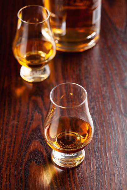 copa de aguardiente de whisky brandy sobre fondo marrón oscuro - Foto, imagen