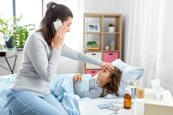 sairas tytär ja äiti soittaa puhelimitse kotona - Valokuva, kuva