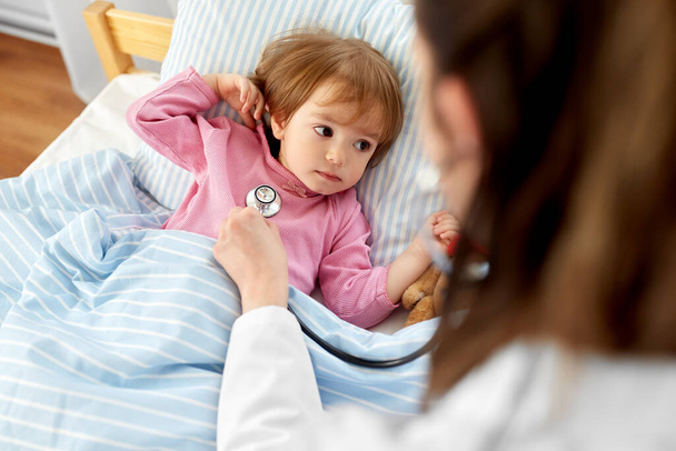 médico con estetoscopio y niña enferma en la cama - Foto, imagen