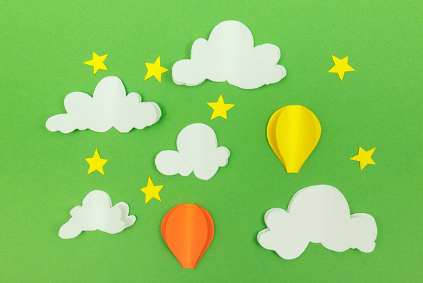 緑の背景にある段ボール雲、星や空気風船。星と雲と空の風船. - 写真・画像