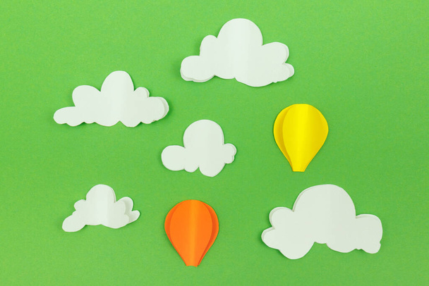 Σύννεφα από χαρτόνι και αερόστατα στο πράσινο φόντο. Μπαλόνια στον ουρανό με σύννεφα. - Φωτογραφία, εικόνα