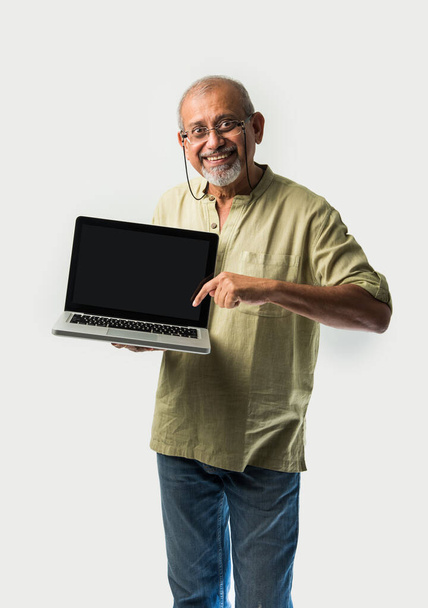 Indian asian senior adult man or grandpa presenting blank laptop screen against white background - Fotografie, Obrázek