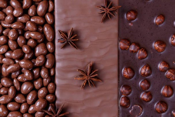 Chocolate bars and chocolate glazed peanuts decorated with anise stars. Chocolate bar with hazelnuts. Chocolate bar with texture. - Photo, Image
