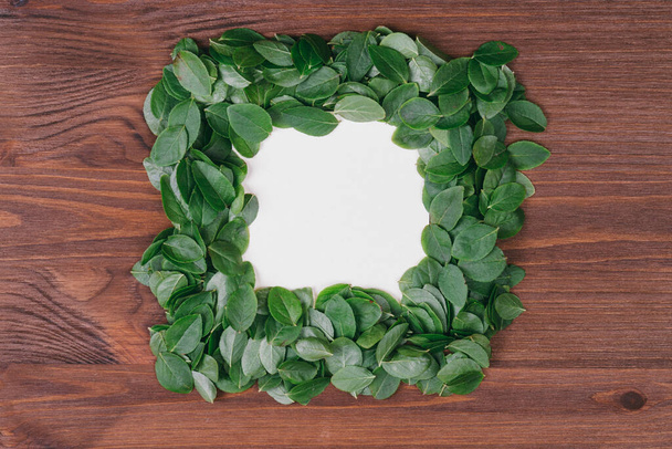 Creative frame made of  leaves with paper card note on a wood background. Flat lay. Nature concept.Top view.  Blank for advertising card or invitation.  - Φωτογραφία, εικόνα