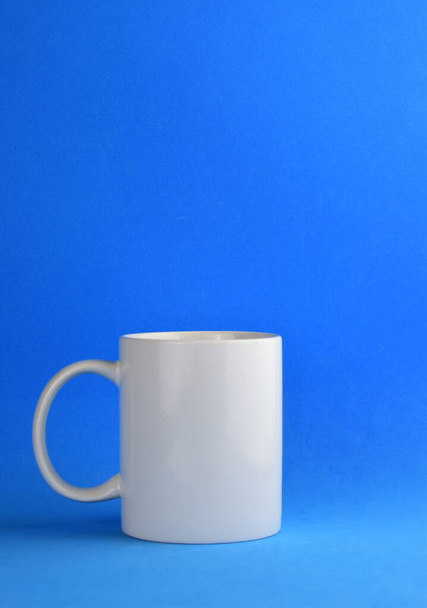Közelkép fehér porcelán csésze, kék háttér és hely a szöveg - Fotó, kép