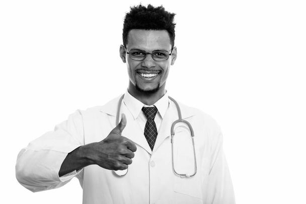 Studio colpo di giovane felice africano uomo medico sorridente mentre dà pollice in su - Foto, immagini