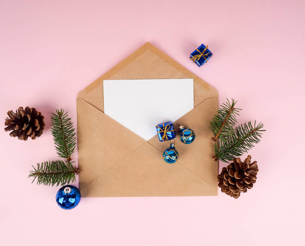 Weihnachtsbaum im Umschlag, minimale Neujahrskarte. Fichtenzweig auf rosa Hintergrund. Urlaub, Gratulationskonzept, blauer Ball. - Foto, Bild