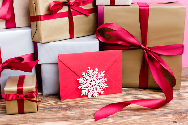 Close up widok pudełek na prezenty, czerwona koperta i dekoracyjne płatki śniegu na drewnianym tle - Zdjęcie, obraz