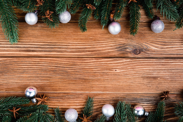 Flat lay with pine branches, christmas balls and anise stars on brown wooden background - Photo, Image