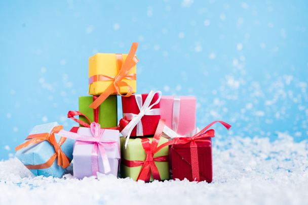 Oppervlakte van miniatuur geschenkdozen met kunstmatige sneeuw op blauw, nieuwjaar concept - Foto, afbeelding