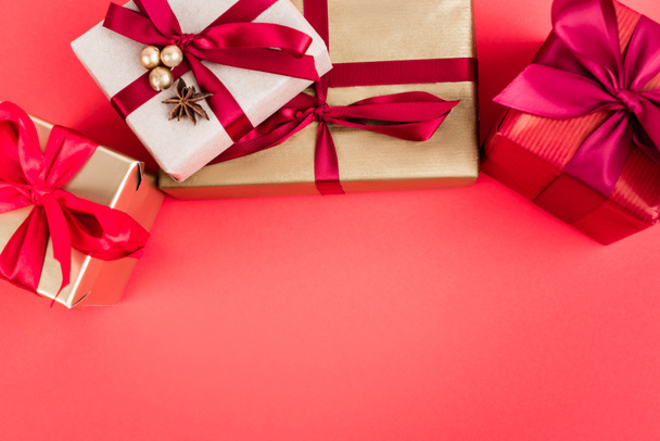 Vista dall'alto di scatole regalo con perline e stella di anice su sfondo rosso, concetto di nuovo anno - Foto, immagini