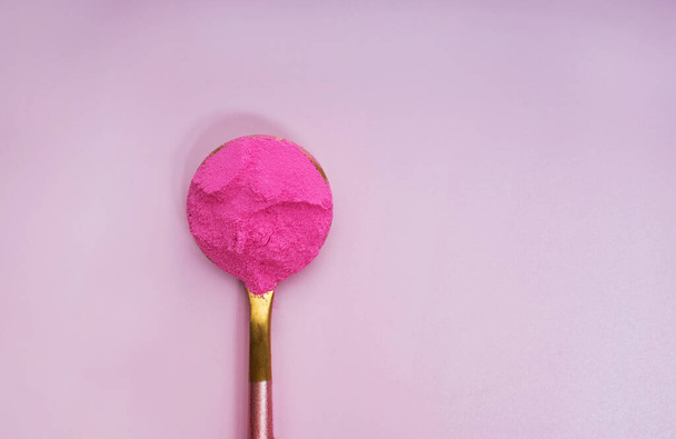 Pink dragonfruit or other superfood powder in a spoon on pink background - Valokuva, kuva