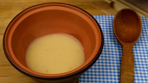 La sopa de guisante crema se vierte en un tazón marrón y se espolvorea con hierbas picadas y croutons fritos. Concepto de comida vegetariana saludable. Primer plano. - Metraje, vídeo