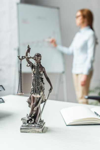 La statuetta sul posto di lavoro con avvocato donna offuscata sullo sfondo - Foto, immagini