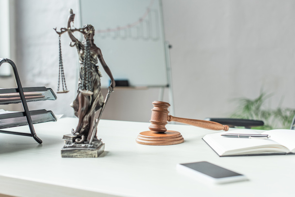 Themis figurine with gavel and wooden block on workplace with blurred flipchart on background - Foto, Imagen