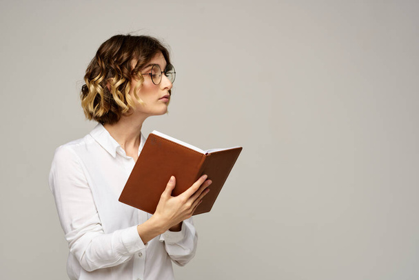 Frau mit Notizblock in den Händen Geschäftsarbeit beige Hintergrund Brille Frisur - Foto, Bild