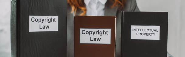 Обрізаний погляд на книги з інтелектуальною власністю та законами про авторське право на розмитому тлі, банер
 - Фото, зображення