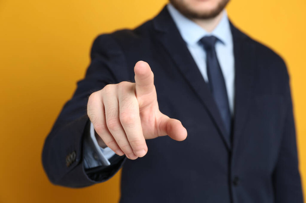 Businessman touching something against orange background, focus on hand - Photo, image