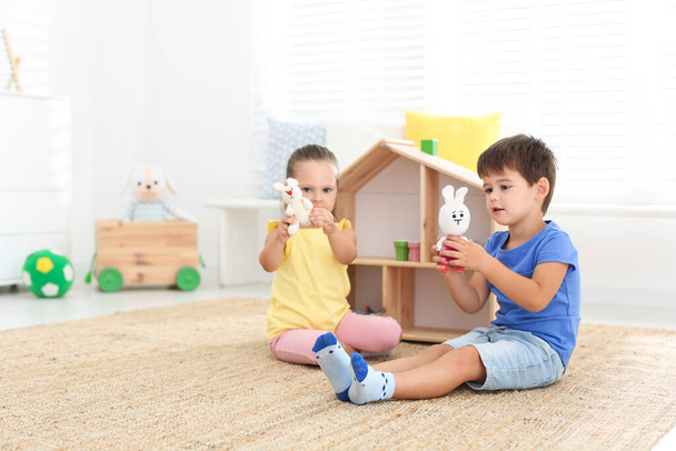 Cute little children playing with toys near wooden house on floor at home - Foto, imagen