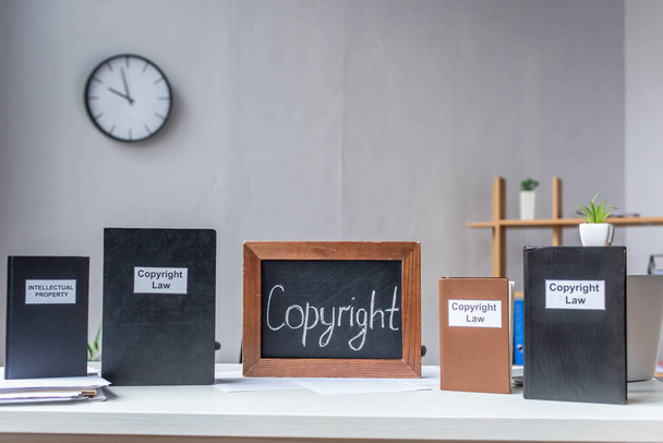 Книги с надписями авторского права и авторского права и доска на столе с кучей документов на размытом фоне - Фото, изображение