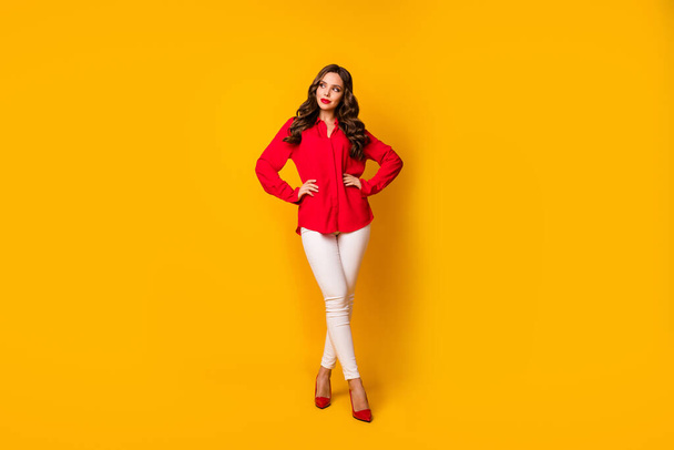 Full length photo of attractive business lady hold hands sides look wondered empty space dreamer wear red office shirt white pants high-heels isolated yellow vibrant color background - 写真・画像