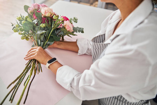 Elegancka kobieta siedząca przy stole z bukietem kwiatów - Zdjęcie, obraz