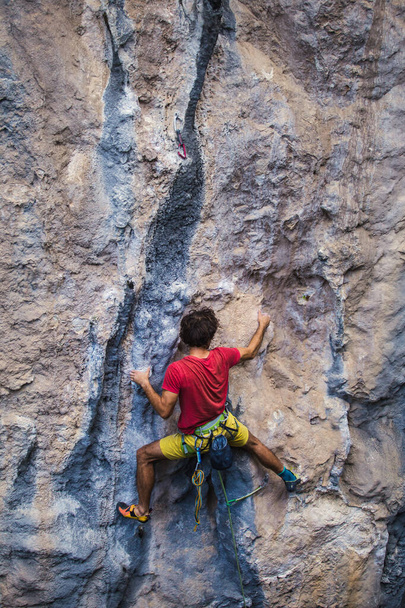 Um homem forte sobe uma rocha, músculos das costas fortes, escalada na Turquia, resistência e força de treinamento, homem em esporte extremo, escalador de rocha está treinando na natureza. - Foto, Imagem