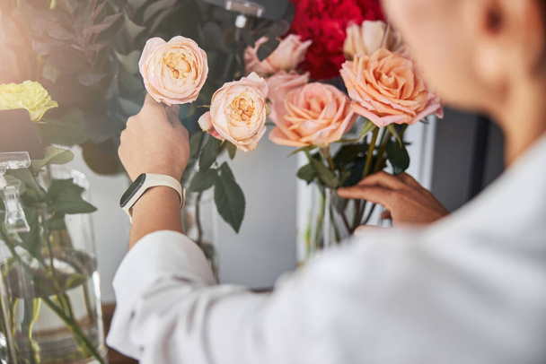 Υπεύθυνη ανθοπώλης βάζει τριαντάφυλλα σε γυάλινα βάζα - Φωτογραφία, εικόνα