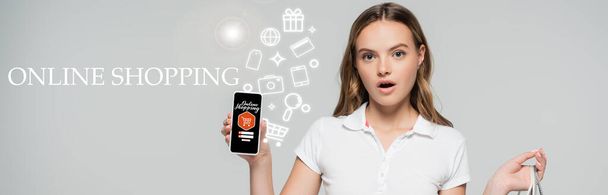 geschokte vrouw met smartphone in de buurt van online winkelen belettering en illustratie op grijs, banner - Foto, afbeelding