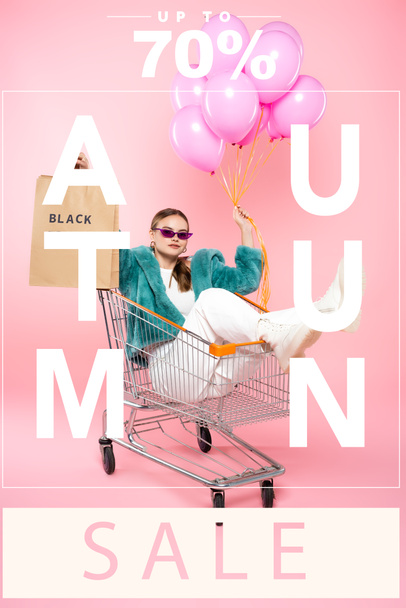 stylish woman in sunglasses sitting in cart with shopping bags and holding balloons near autumn sale lettering and tag on pink  - 写真・画像