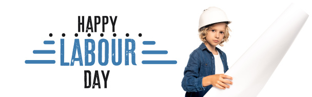 niño con casco de seguridad y traje de arquitecto sosteniendo plano feliz día del trabajo letras en blanco, bandera - Foto, Imagen
