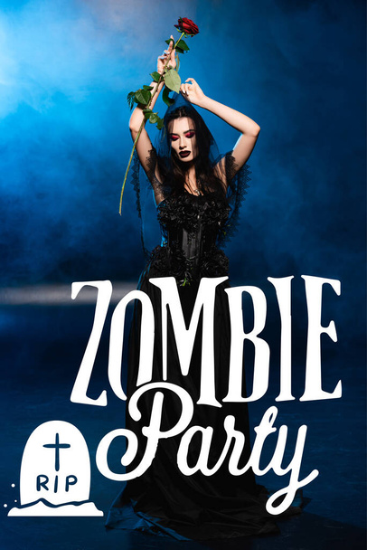 bride in black dress and veil holding red rose above head near zombie party lettering on blue with smoke - Photo, Image