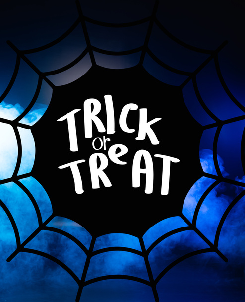 trick or treat lettering and spider web illustration on dark blue background  - Photo, Image