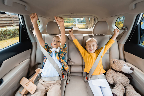 Hymyilevä lapset osoittavat kyllä ele istuessaan lähellä leluja auto  - Valokuva, kuva
