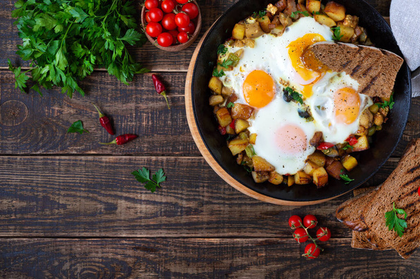 Τηγανητά αυγά με λαχανικά - shakshuka σε τηγάνι και ψωμί σίκαλης σε παλιό ξύλινο φόντο. Πρωινό αργά. Ρουστίκ στυλ. Παραδοσιακό πιάτο της Μέσης Ανατολής. Επίπεδη. Άνω όψη - Φωτογραφία, εικόνα
