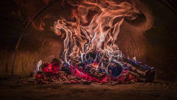 Leña de fuego cocinando una pizza dentro de un horno de piedra - Foto, imagen