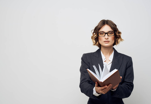 Business woman with a book in her hands on a light background classic suit fashionable hairstyle Copy Space - 写真・画像