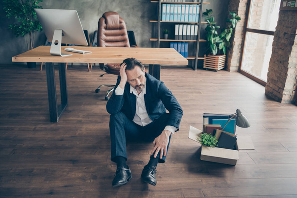 Above high angle view of his he depressed desperate jobless guy lawyer attorney sitting on floor with card box belongings things at modern loft industrial brick style interior workplace workstation - Photo, Image