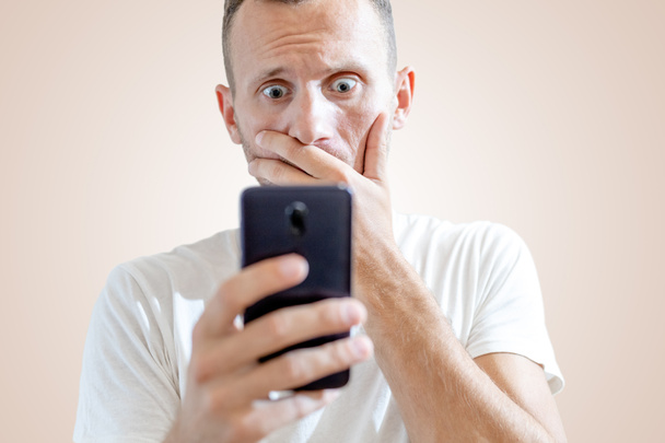 joven europeo hombre mirando el teléfono inteligente con miedo - Foto, Imagen