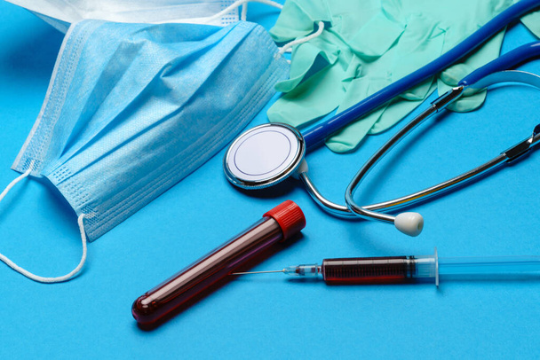 Top view of Medical equipment and tools on blue background - stethoscope, surgical mask, medical gloves, syringe and test tube - healthcare and medicine concept. Medical banner design - Photo, image