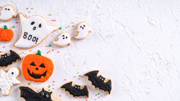 Top view of Halloween festive decorated icing gingerbread sugar cookies on white background with copy space and flat lay layout. - Foto, immagini