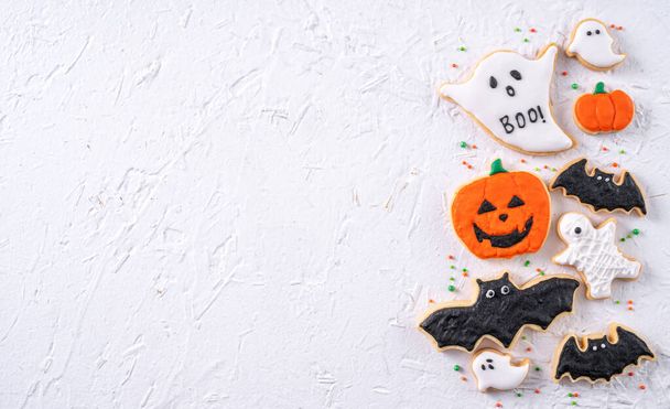 Top view of Halloween festive decorated icing gingerbread sugar cookies on white background with copy space and flat lay layout. - Fotografie, Obrázek