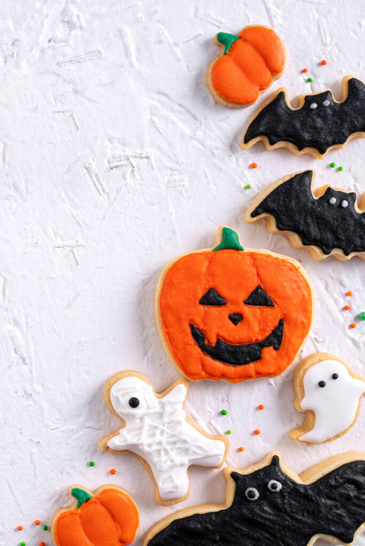 Top view of Halloween festive decorated icing gingerbread sugar cookies on white background with copy space and flat lay layout. - Zdjęcie, obraz